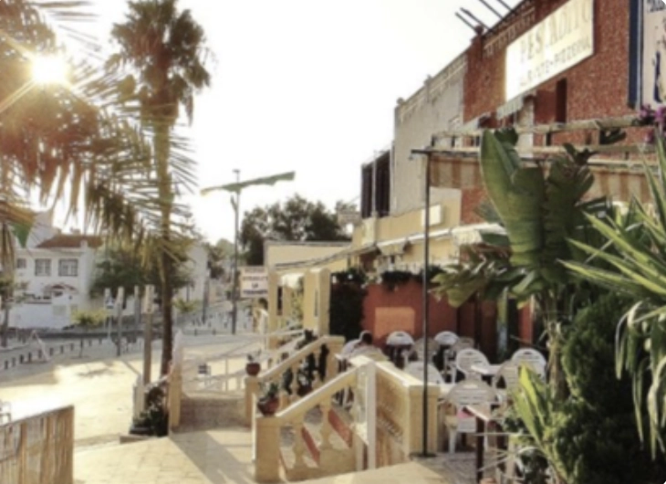Sunny street with palm trees and cafe in Mil Palmeras